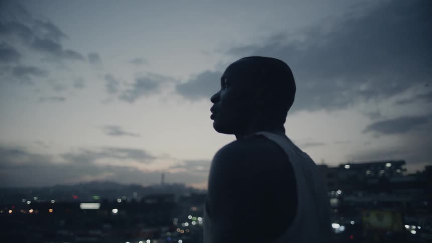 A man is watching the clouds in the sky from a rooftop at dusk