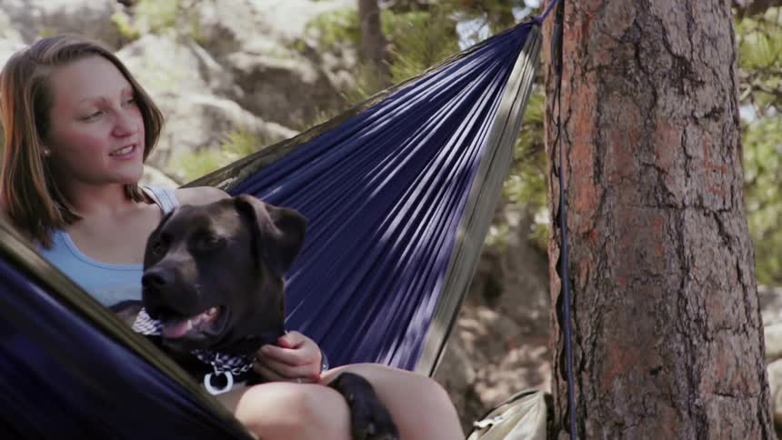 Woman and dog swing in a hammock