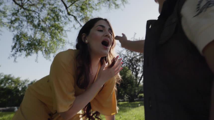 A mother opening her mouth playfully while engaging with her child outdoors.