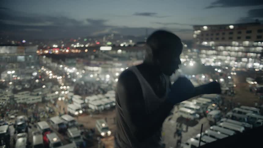 A boxer punches the air on a building rooftop