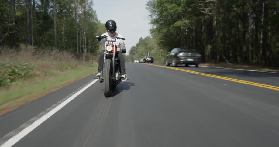 Man motorcycles on a tree-lined road