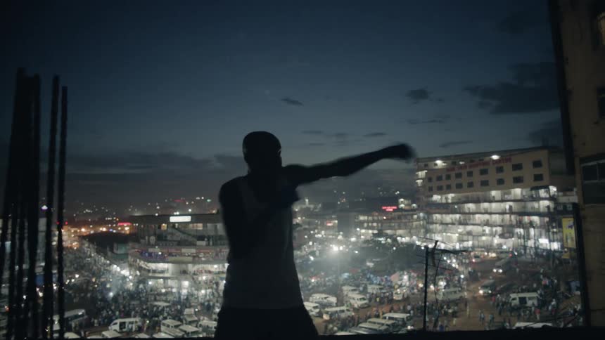 A boxer is shadow boxing on a rooftop at night