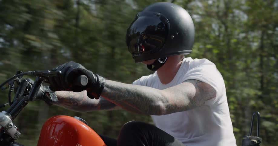 Man drives a motorcycle on a tree lined country road