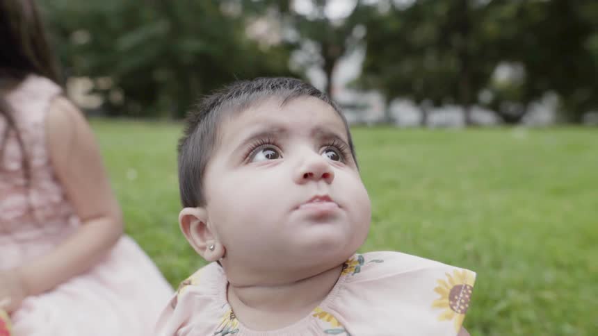 Close up of an adorable baby looking up with wide curious eyes outdoors.
