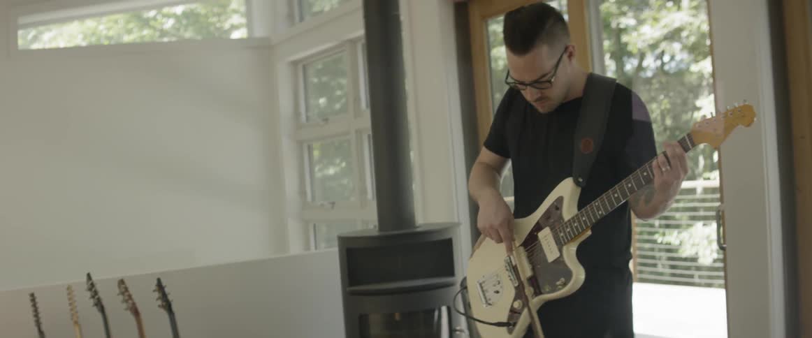 A man plays guitar with a bow