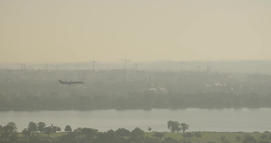 A plane flies over a city at sunset
