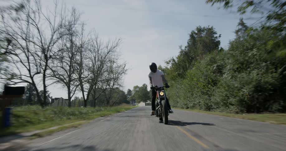 Man stands up while driving at motorcycle on a country road