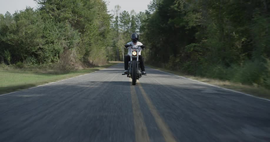 A motorcyclist rides on a rural road