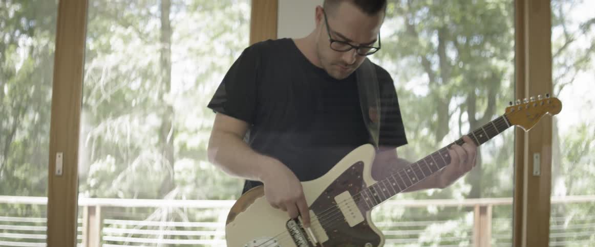 A man plays an electric guitar with a bow