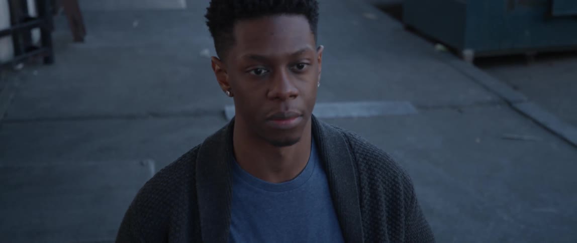 A man stares straight ahead while standing on a sidewalk