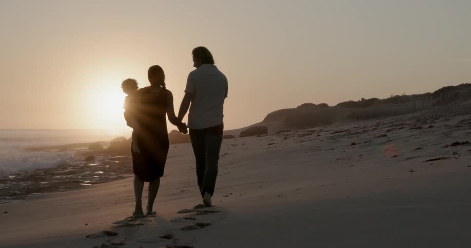 Couple with child walk along beach
