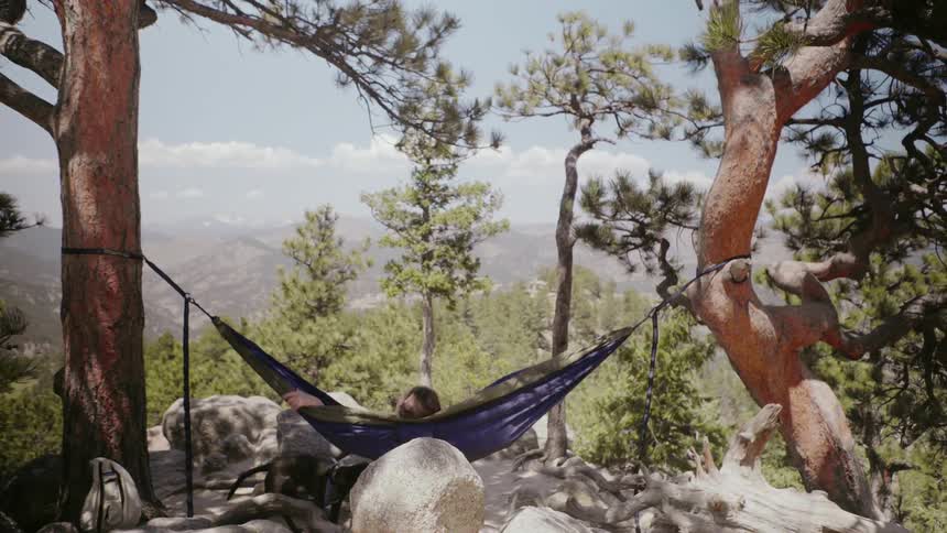 A woman swings in a hammock in mountains