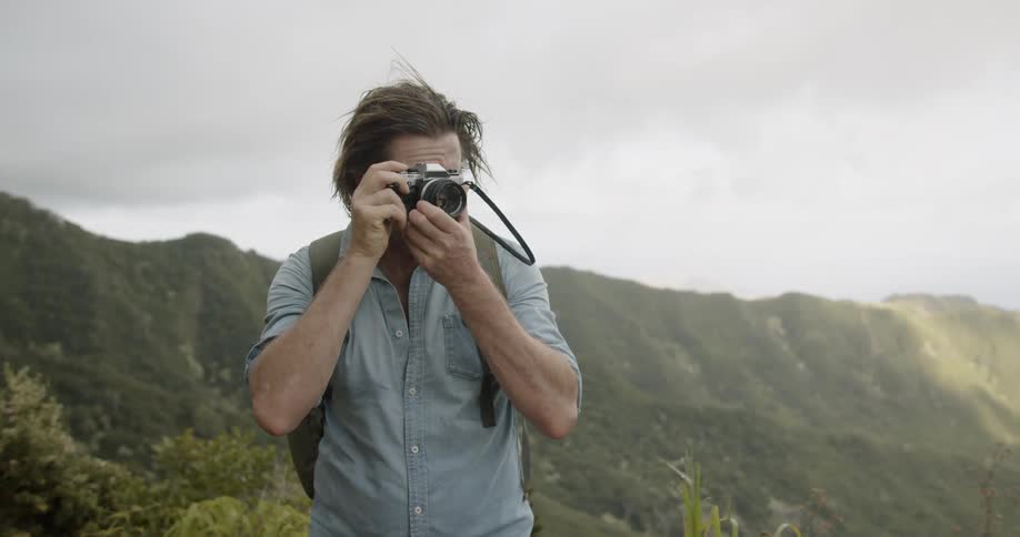 A man takes a photo while hiking in mountains