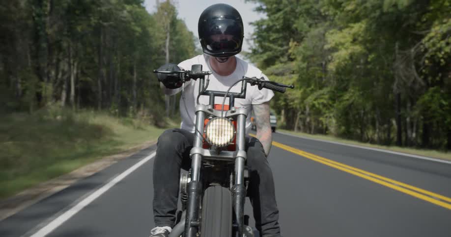 Man motorcycles on a tree-lined road