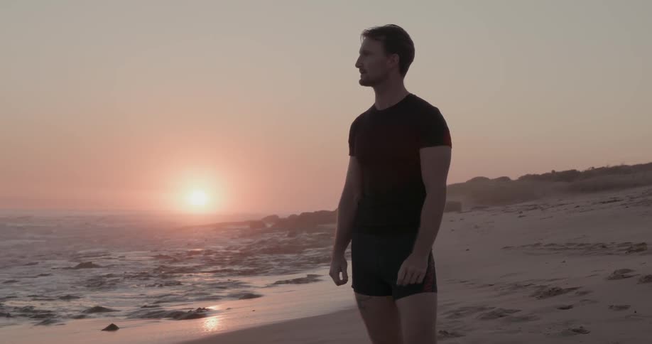 Man stands on a beach at sunset