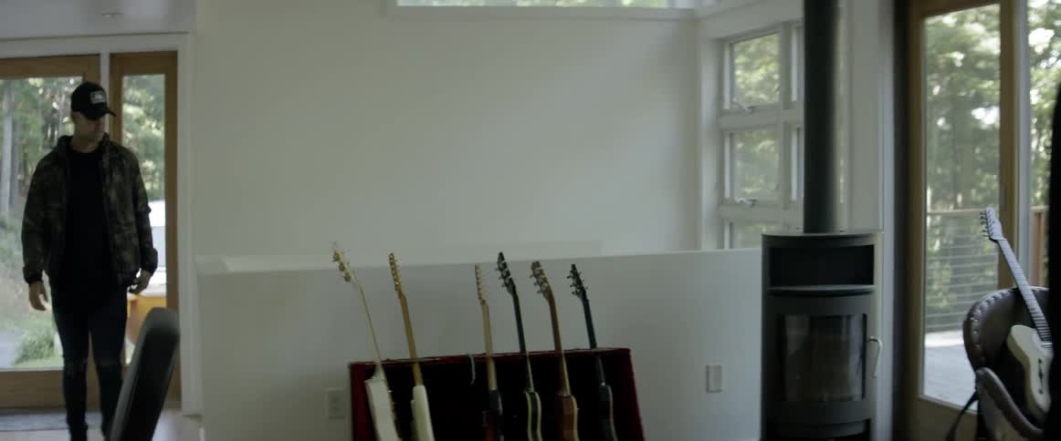 Two men enter a music room with guitars and a keyboard