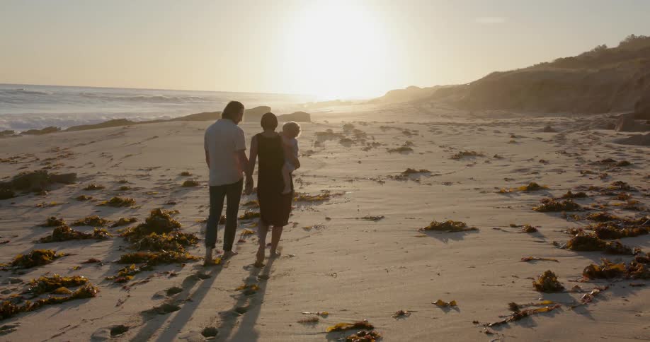 Couple with child walk along beach