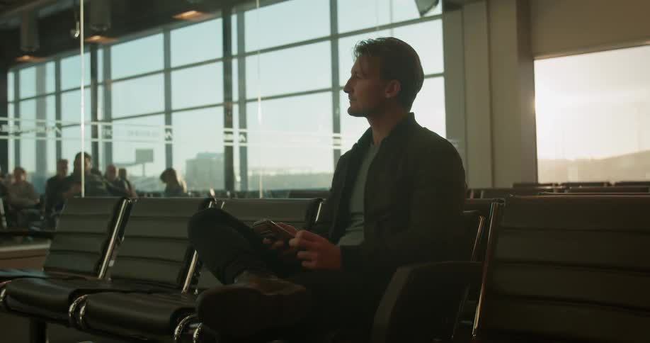 A man uses his phone while waiting at an airport