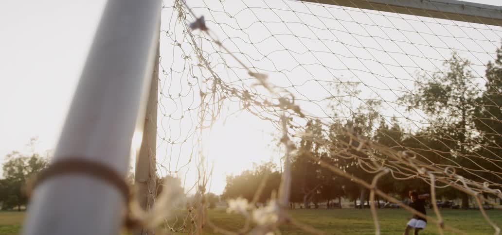 Boy kicks soccer ball into goal