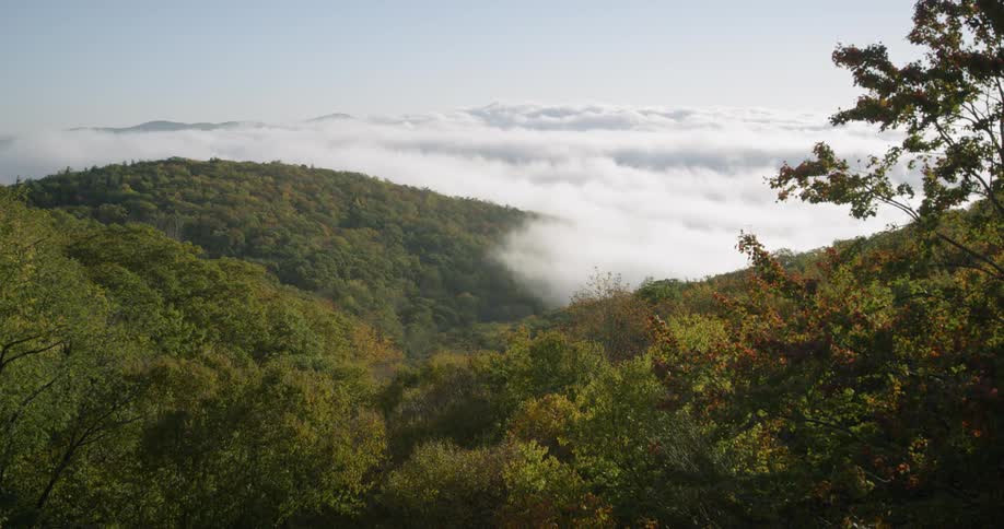 Clouds float over rural trees and hills