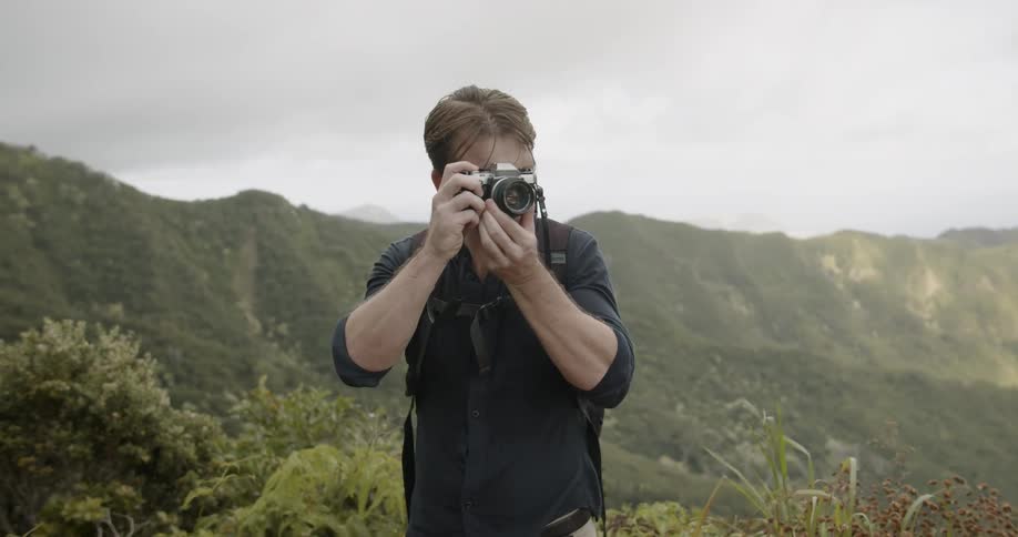 Man takes a photograph while hiking in mountains