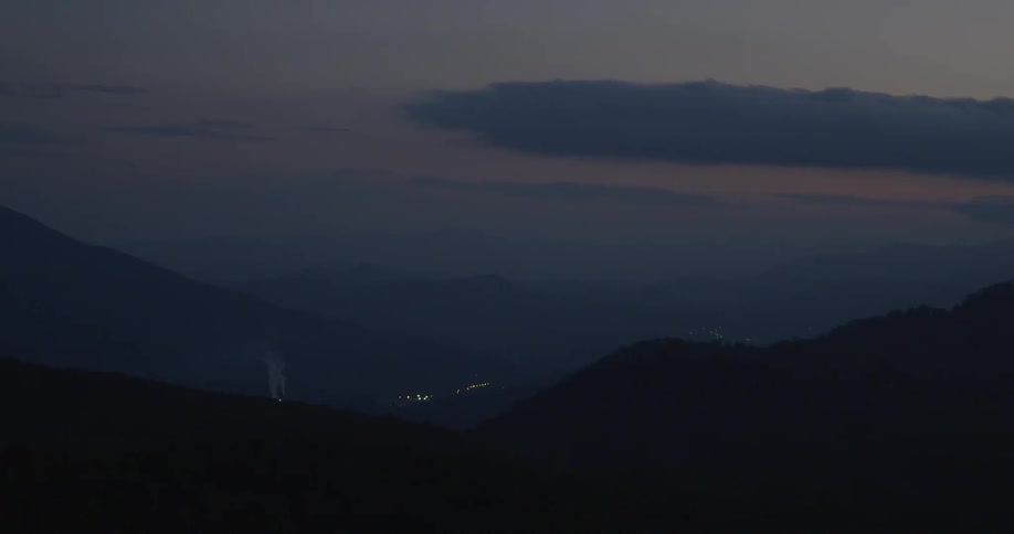 Clouds float over mountains at dusk