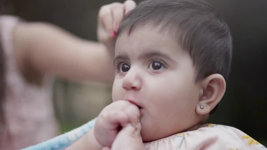 Close up of a gentle hand caressing a cute baby's head outdoors.