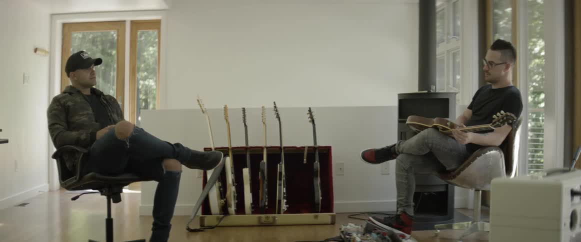 Two men talk in a music studio