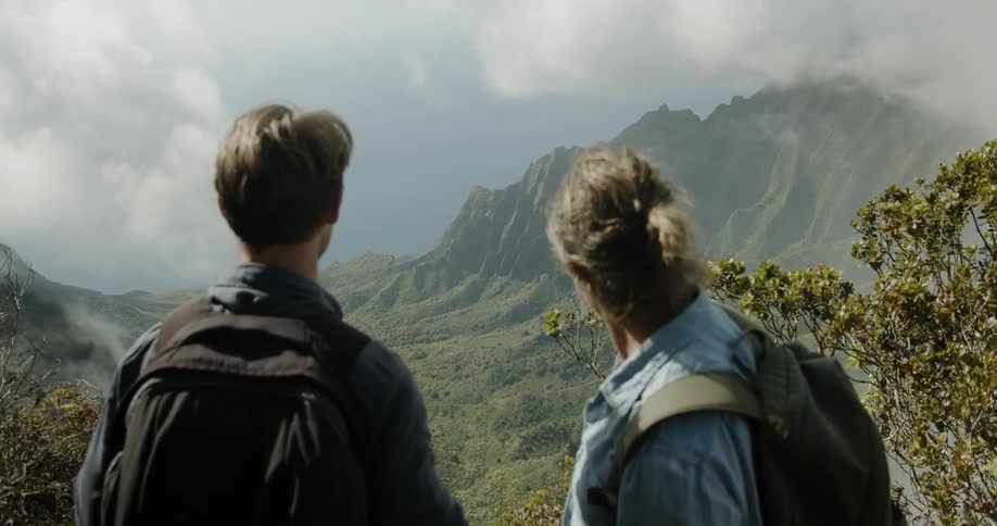 Two men are taking in a view of a mountain valley on a cloudy day