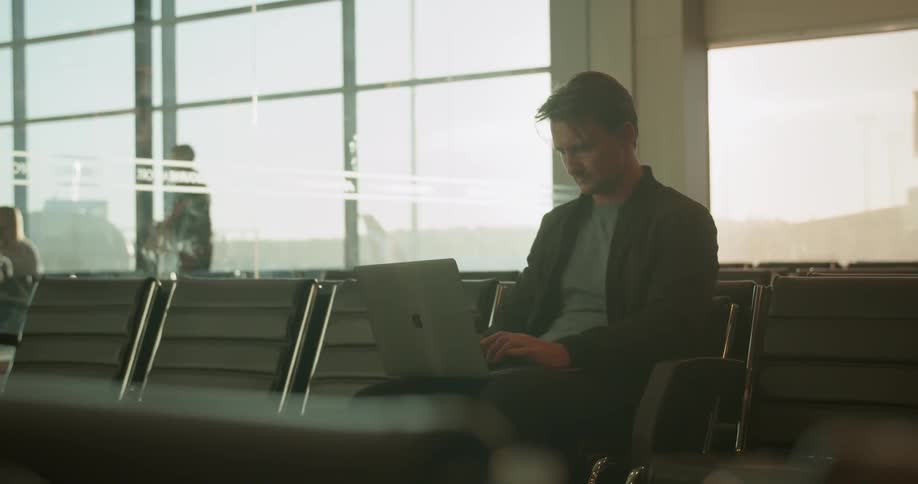Man types on a laptop in an airport