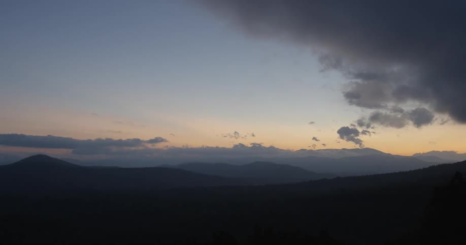 Clouds float over mountains at sunset