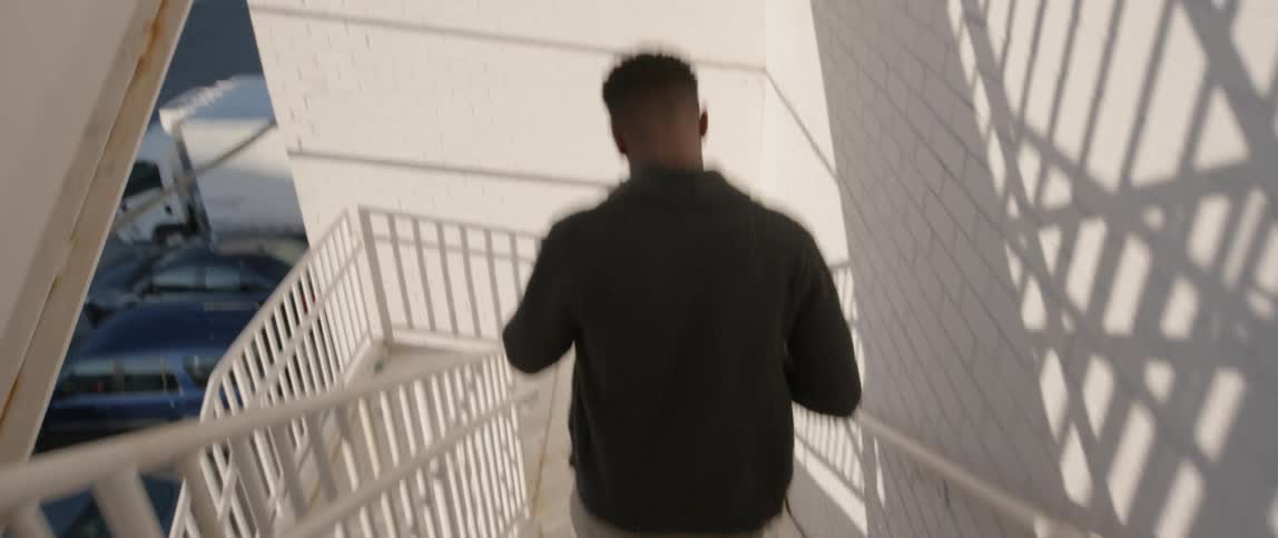 A man is going down a set of stairs outside a building in daylight
