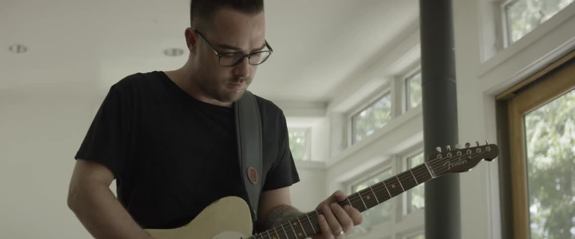 Man looks down while playing a guitar