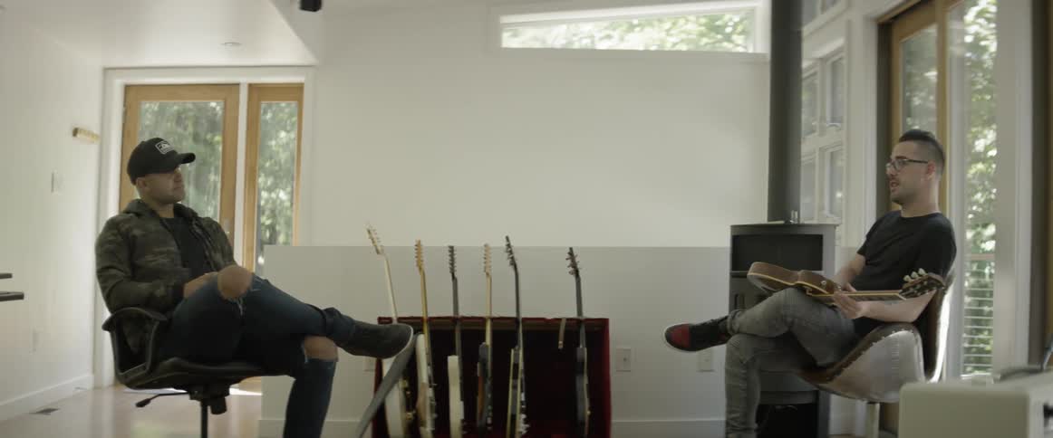 Two men talking near guitars