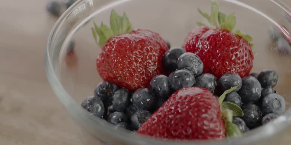 Sugar is sprinkled on a bowl of blueberries and strawberries