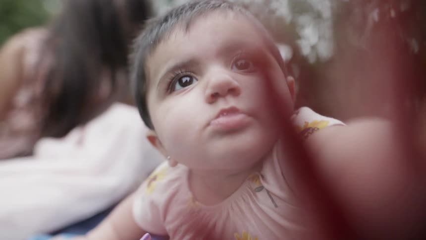 Close up of a baby reaching hand toward camera with a curious expression.