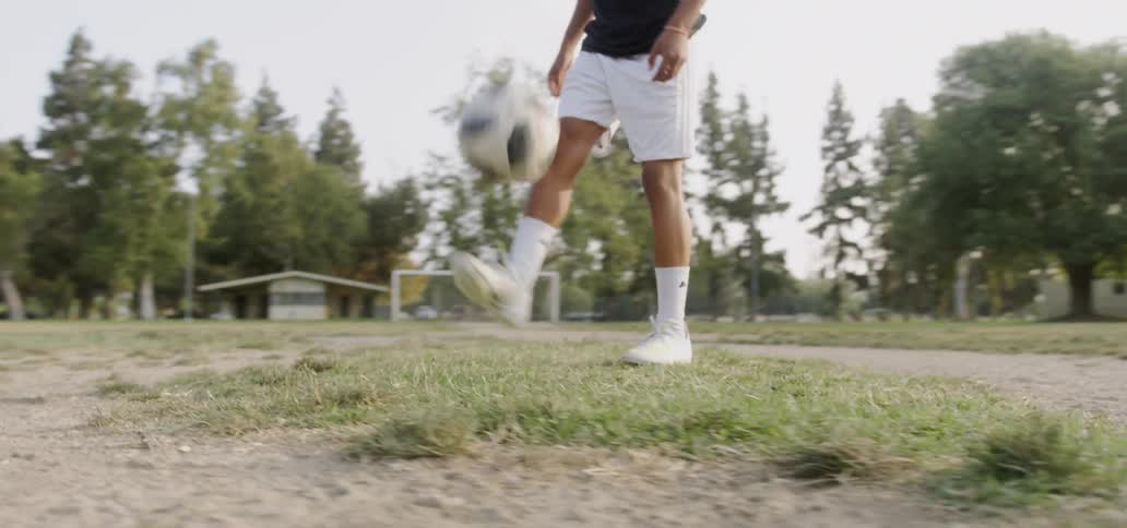 Person is kicking soccer ball into the air on soccer field