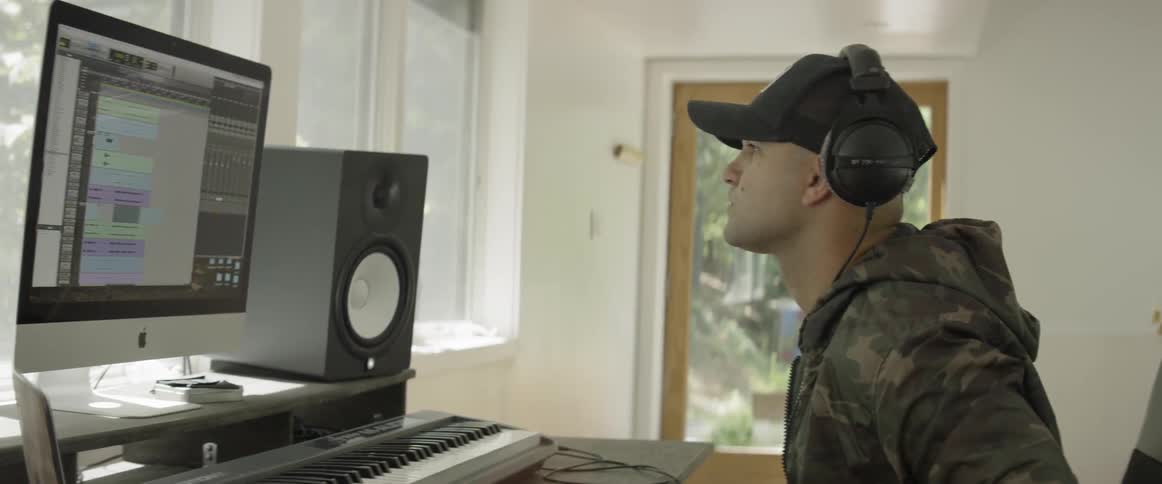 A man is composing music inside using a computer in daylight