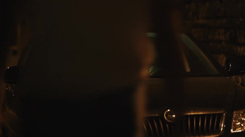 A man and woman talk in a parked car at night