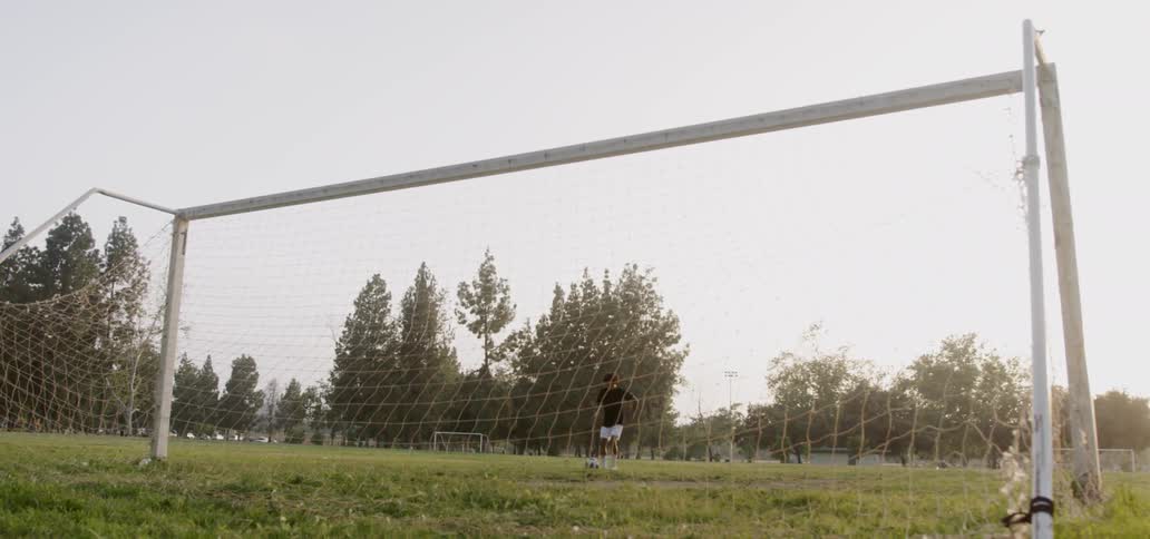 Boy kicks soccer ball towards goal post
