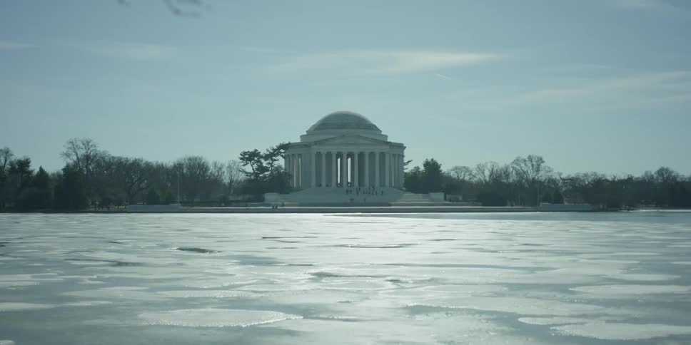 Large ice covered lake in front of a white building with many tall pillars