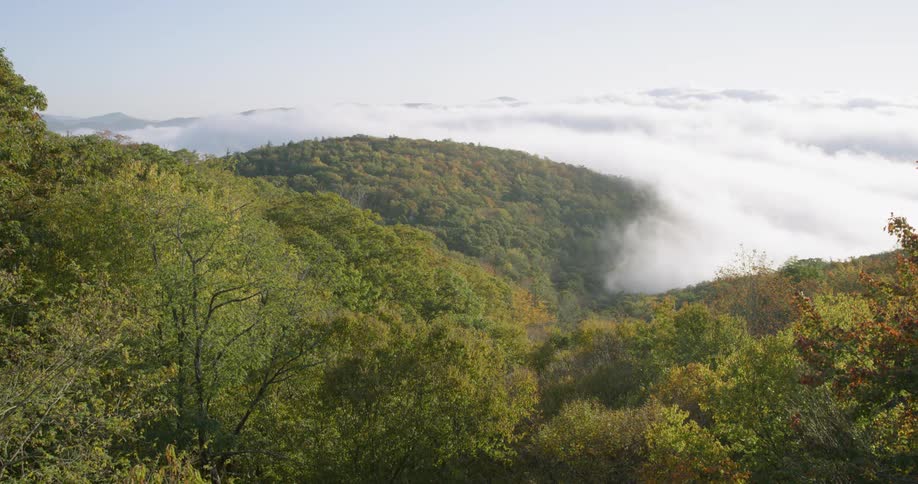 Clouds float over rural trees and hills