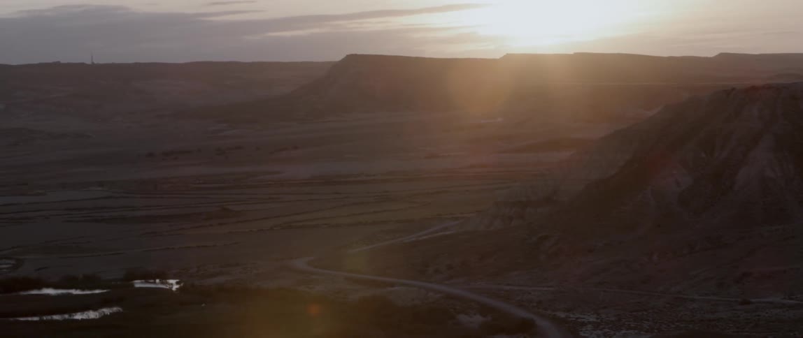 The sun sets over a rural mountain landscape