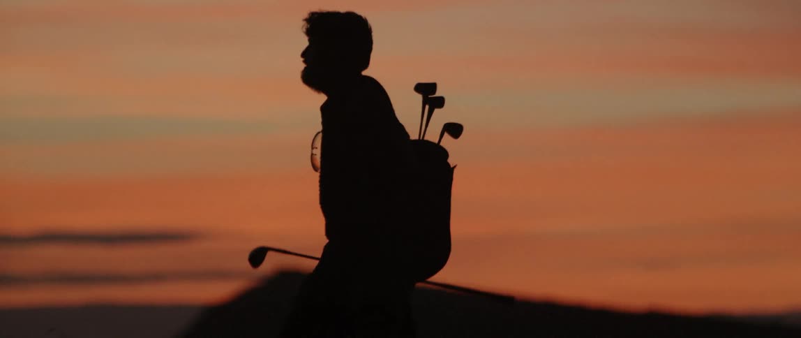 A man plays golf at dusk