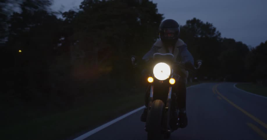 A motorcyclist travels on a rural road at night