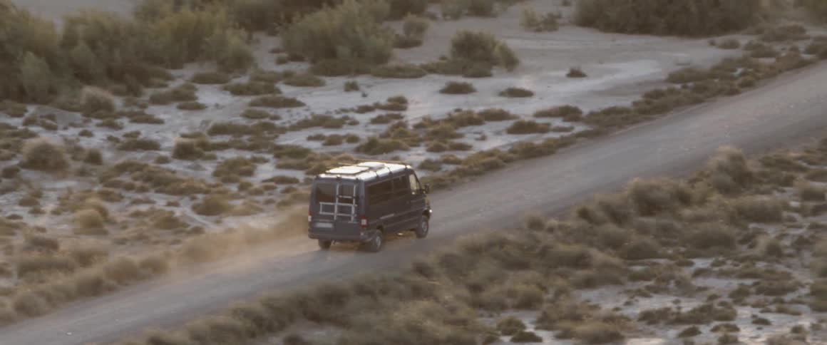 a mercedes bus drives trough the desert