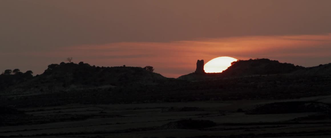 The sun sets behind mountains
