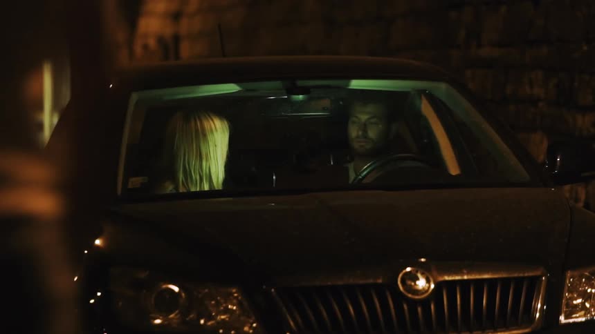 Man and woman sit in a parked car at night