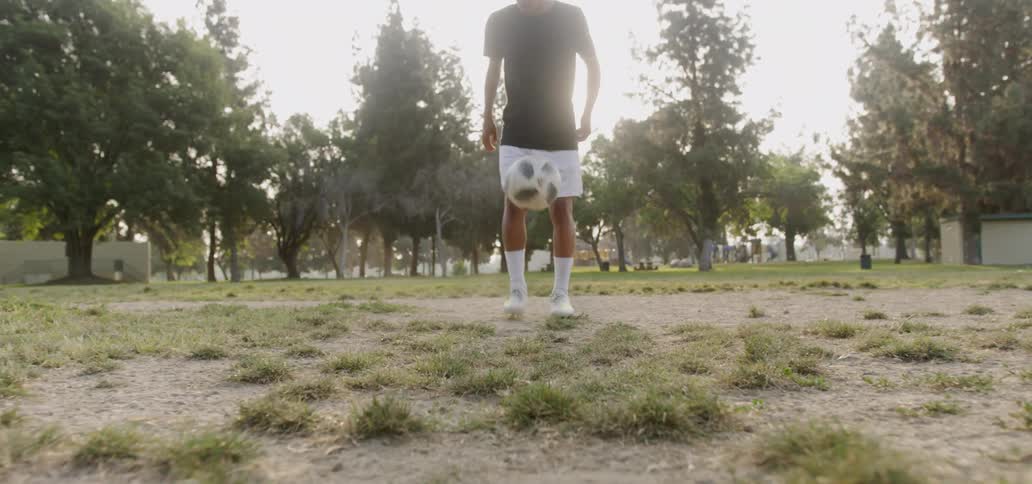 Man kicks a soccer ball as he stands in a field