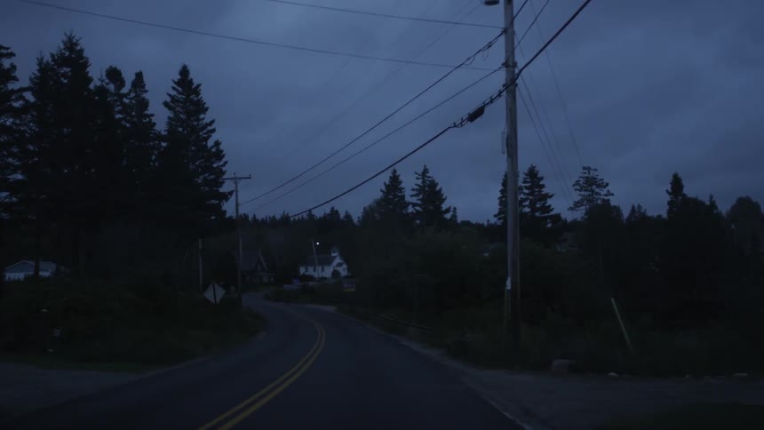 Driving down a quiet highway beneath power lines at dusk